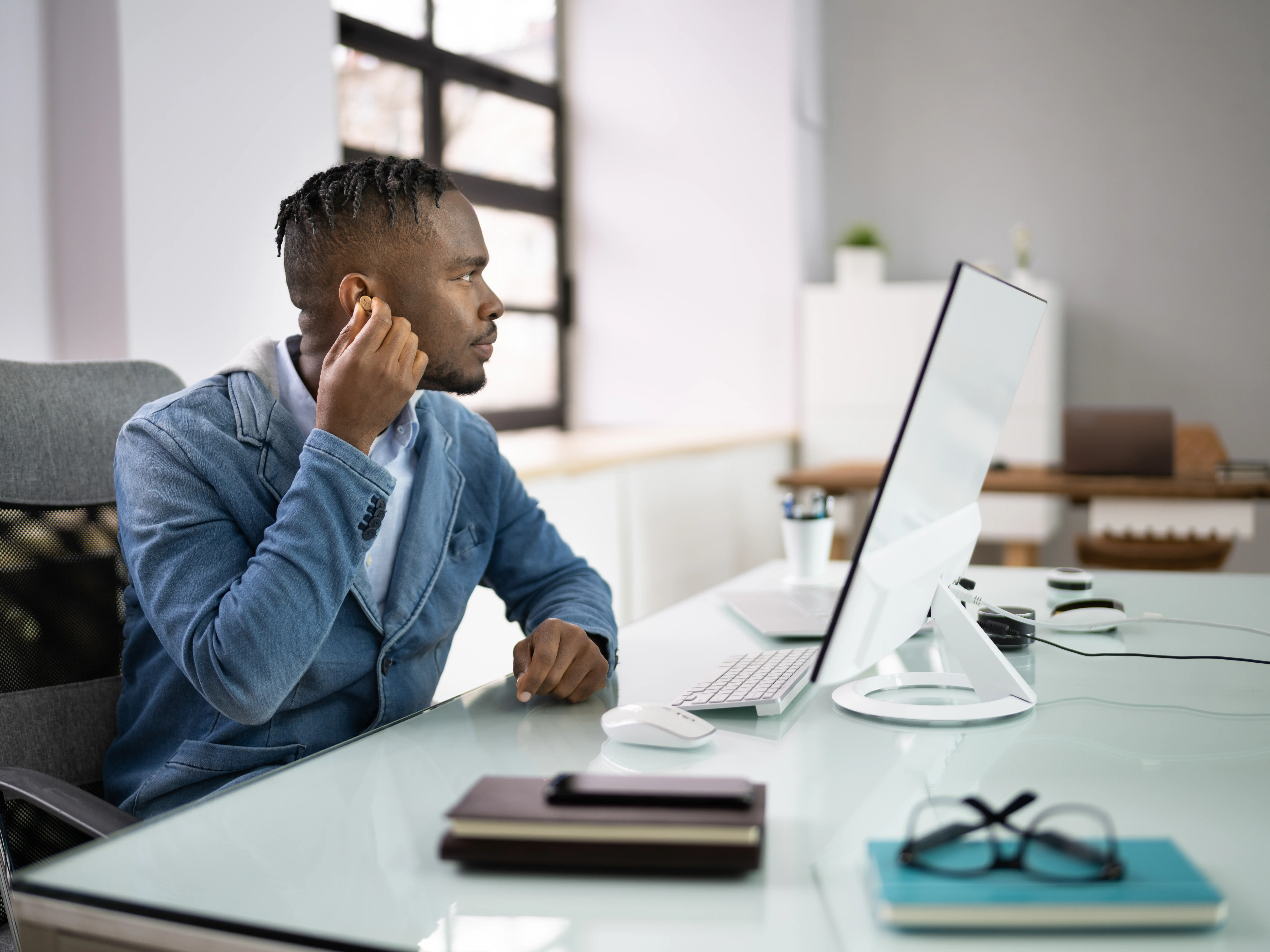 Man adjusting his hearing aids in the office
